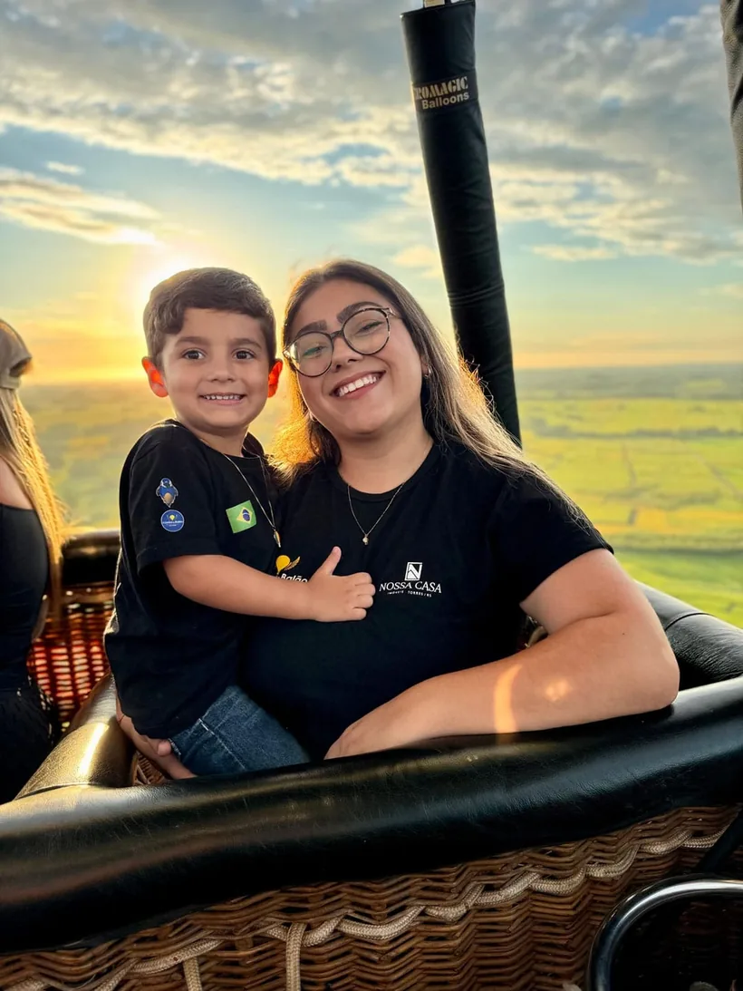 Mãe e filho sorrindo dentro do cesto do balão durante o voo ao nascer do sol